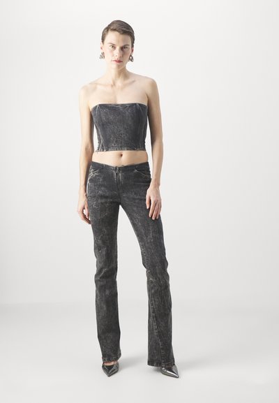 Mustast denimist crop top ja flared-püksid pleekinud viimistlusega. Metallilised teravad kontsad ja suured hõbedased kõrvarõngad täiendavad riietust.