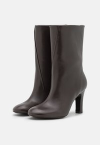 Svarta läderanklar med spetsig tå och en avsmalnande design, med en medelhög klack och en slät, glänsande yta.