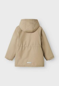 Beige waterdichte jas met een afneembare capuchon, lange mouwen en een taillekoord. Beschikt over een reflecterende accent nabij de zoom.