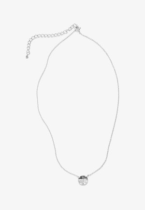 Collier délicat en chaîne d'argent avec un petit pendentif rond martelé en argent et un fermoir ajustable sur fond blanc.
