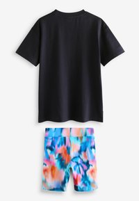 Mornarska pamučna majica kratkih rukava uz šarene tie-dye kratke hlače s plavim, ružičastim i narančastim uzorcima od glatkog, rastezljivog materijala.