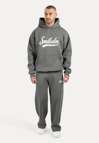 Conjunto de sudadera y pantalones de chándal grises con un logo blanco de "Smilodox". Hecho de una tela suave, con un bolsillo frontal y un ajuste holgado.
