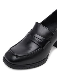 Fekete bőr loaferek sima felülettel, díszítő pánttal a felsőrészén, és bordázott gumitalppal a tapadás érdekében.