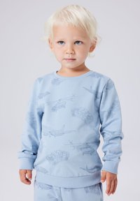 Jasnoniebieska bluza z okrągłym dekoltem, z konturowymi ilustracjami pojazdów, w tym samolotów i samochodów, na miękkiej tkaninie z mieszanki bawełny.