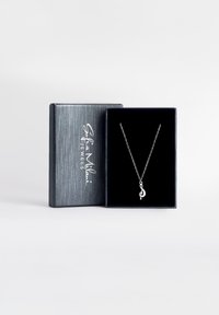 Collier en chaîne argentée avec un pendentif en forme de note musicale, présenté dans une boîte doublée de velours noir, dotée d'un extérieur en gris texturé.