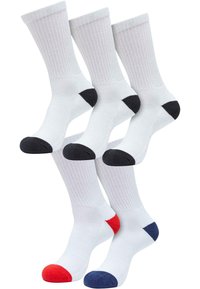 Fünf weiße Crew-Socken, drei mit schwarzem Fersen- und Zehenbereich, eine mit rotem Fersen- und Zehenbereich und eine mit dunkelblauem Fersen- und Zehenbereich, aufrecht angeordnet.