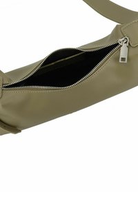 Khaki leren tas met een gladde textuur, voorzien van een zilveren rits en een enkele schouderriem. Geopende zak toont een zwarte binnenkant.