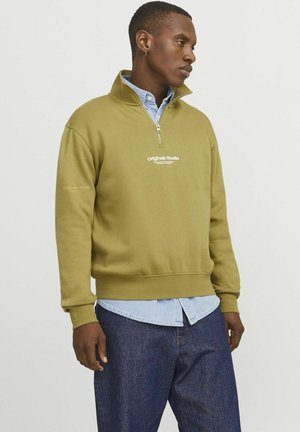 Olive green, zip-neck sweatshirt with ribbed cuffs and hem; features white "Originals Studio" logo on the chest and layered light denim shirt.