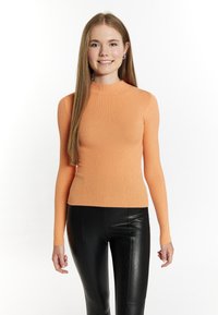 Maglione a collo alto rigato in pesca-arancio, maniche lunghe, vestibilità aderente, abbinato a pantaloni in ecopelle nera. Sottile texture su tutta la superficie.