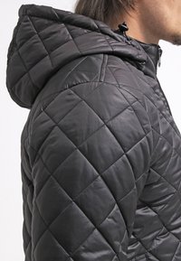 Czarna pikowana kurtka z fakturowanym, ocieplanym wzorem. Posiada kaptur z regulowanymi sznurkami oraz zamek błyskawiczny z przodu.