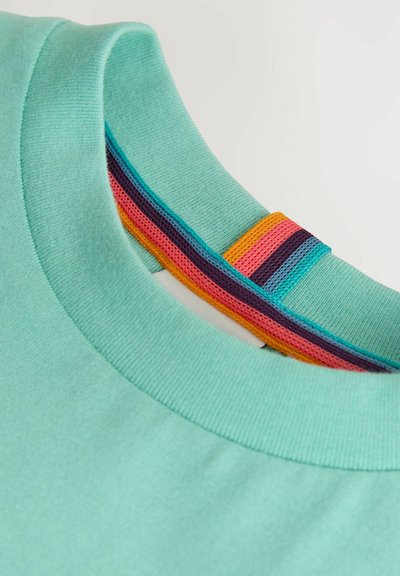 Nærbillede af en lyseturkis T-shirt med rund halsudskæring med farverig inderkant i striber i orange, pink, lilla og blå.