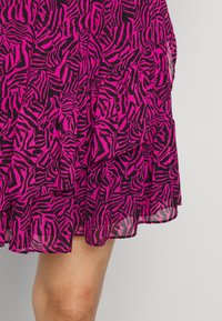 Falda fucsia con rayas de cebra negras, que presenta un diseño de volantes en capas y una textura translúcida. La parte inferior cae por encima de la rodilla.