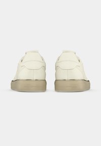 Χαμηλά αθλητικά παπούτσια σε εκρού δέρμα, με λεία υφή, ταμπά λαστιχένια σόλα και μινιμαλιστικό σχεδιασμό με ραμμένες λεπτομέρειες.