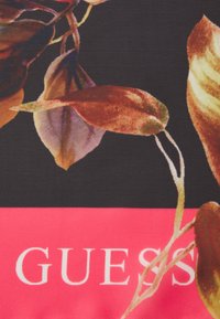 Lilleline disain, kus tumepruunid ja rohelised lehed paiknevad mustal taustal, roosa lindiga, millel on bold valged tähed sõnaga "GUESS".