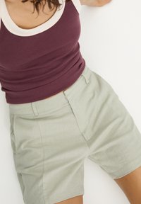 Burgundowy prążkowany top na ramiączkach z kremową lamówką, zestawiony z jasnooliwkowymi szortami z przednimi kieszeniami i luźnym krojem.
