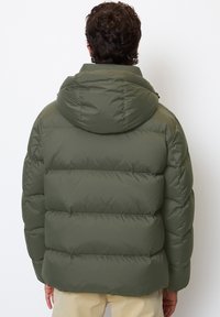 Olive green puffy jacket with a hood, featuring horizontal quilted sections and elastic cuffs. Back view shows soft, smooth texture.