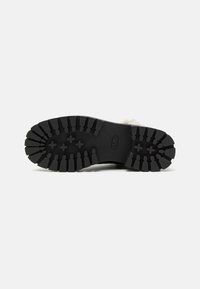 Black rubber boot sole with deep treads, structured for traction. Reinforced design with textured surface and curved edges.