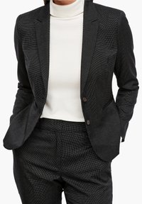 Czarna marynarka o fakturze, dopasowana, z klapami, na dwa guziki i pasującymi spodniami. Noszona na białym golfie.