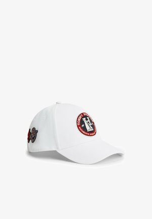 Biała czapka bejsbolowa z okrągłą naszywką z logo Tommy Hilfiger z przodu oraz numerem "85" wyhaftowanym na boku w czerni i czerwieni.