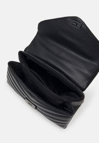 Czarna skórzana torebka z pikowanym wzorem i klapą. Posiada dwie przegrody wyłożone materiałem oraz elegancki, minimalistyczny detal metalowy.