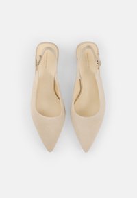 Beige ruskinn slingback-hæler med spisse tær, glatt tekstur og sidebøylelås. Innvendig har de en lett polstret såle.