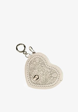 Porte-clés en cuir beige en forme de cœur avec un motif floral découpé complexe, anneau métallique et attaches à clip.