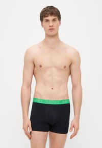 Boxers pretos com cintura elástica verde "HAPPY". Material macio, design ajustado e comprimento até a metade da coxa.