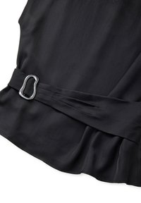 Abito nero con una cintura larga caratterizzata da una fibbia d'argento irregolare, tessuto morbido e orlo leggermente arricciato.