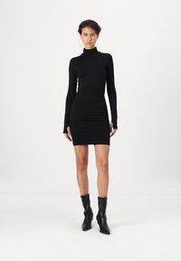 Melnā garo piedurknu kleita ar augstu kakla izgriezumu un piegulošu siluetu. Audums ir gluds un stiepjas, izceļot ķermeņa formas.