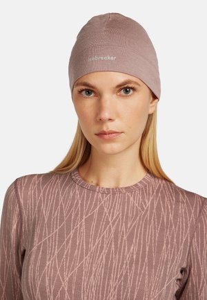 Hellblauer Beanie aus einem weichen, dehnbaren Stoff. Verfügt über ein dezentes Logo und ein figurbetontes Design. Darunter ein strukturierter Langarm-Oberteil.