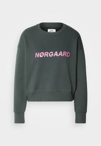 Sweat-shirt vert foncé à manches longues avec texte rose "NØRGAARD" sur le devant et col rond.