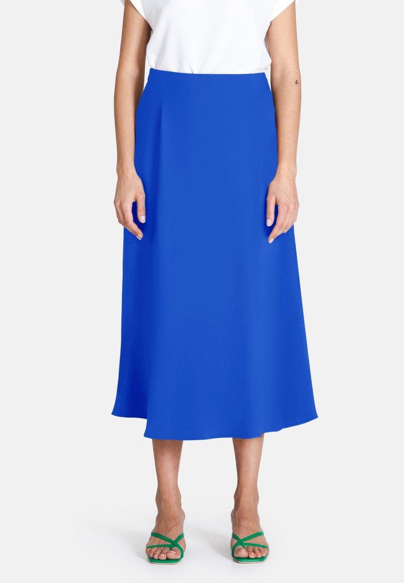 Medellång, solid blå kjol gjord av ett mjukt, lätt material. Minimalistisk design med en figurnära midja och strömmande silhuett.