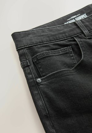 Svarta denimjeans med en figurnära design, standardfickor och kontrasterande sömmar vid midjan och fickorna.