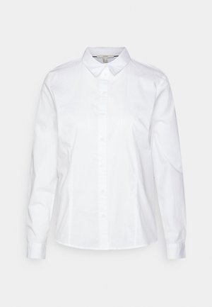 Bílá košile s dlouhým rukávem a knoflíkovou légou, s klasickým límečkem, vyrobená z hladké bavlny. Má přední légu a manžety na jeden knoflík.