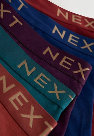 Päť párov bavlnených boxerských trenírok navrstvených na sebe, s farebnými pásmi v páse: červený, modrý, tmavofialový, tyrkysový a zlaté logo "NEXT".