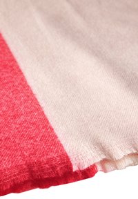 Tissu rayé rouge et rose clair avec une surface douce et texturée. Le matériau semble tricoté avec un léger élasticité et un bord effiloché.