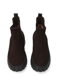 Brązowe botki z zamszu z masywną czarną gumową podeszwą, elastycznymi panelami po bokach oraz pętlami do łatwego zakładania. Gładka faktura i zaokrąglony nos.