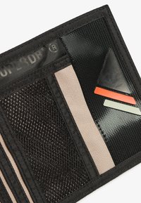 Portafoglio nero con pannelli in rete e lisci, caratterizzato da un logo, accenti geometrici in rosso e verde, e un tessuto testurizzato.