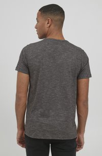 Camiseta gris de manga corta en un tejido de punto texturizado con cuello redondo y corte recto. Sin logotipos ni patrones visibles.