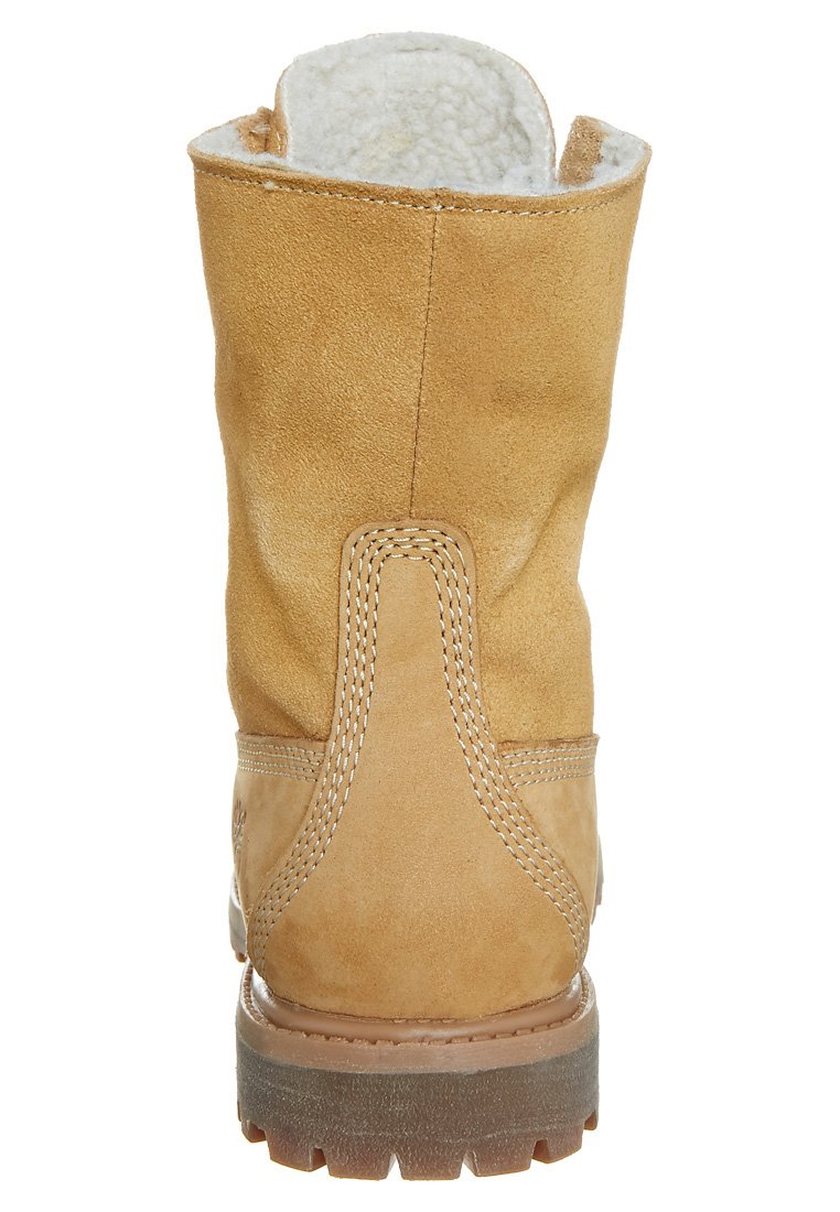 Bottines en daim beige avec une finition texturée et un doublure intérieure douce, présentant une semelle en caoutchouc robuste et des détails de couture contrastants.