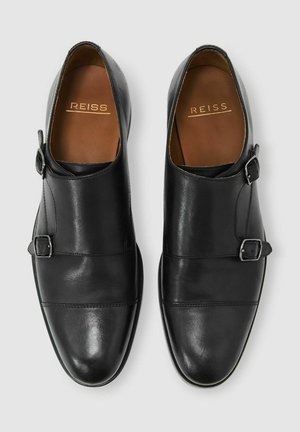 Pantofi negri din piele cu un design elegant, accentuati de două catarame, textură netedă și vârf rotund. Logo-ul brandului este vizibil în interior.