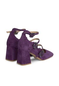 Scarpe in suede viola con tacco a blocco, dotate di più cinturini e fibbie decorative sui lati. Design a punta e texture morbida.