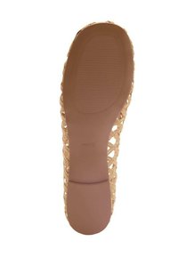 Soletta piatta intrecciata di colore tan con una base in gomma marrone liscia, caratterizzata da un motivo di grip testurizzato e un design superiore a forma di graticcio.