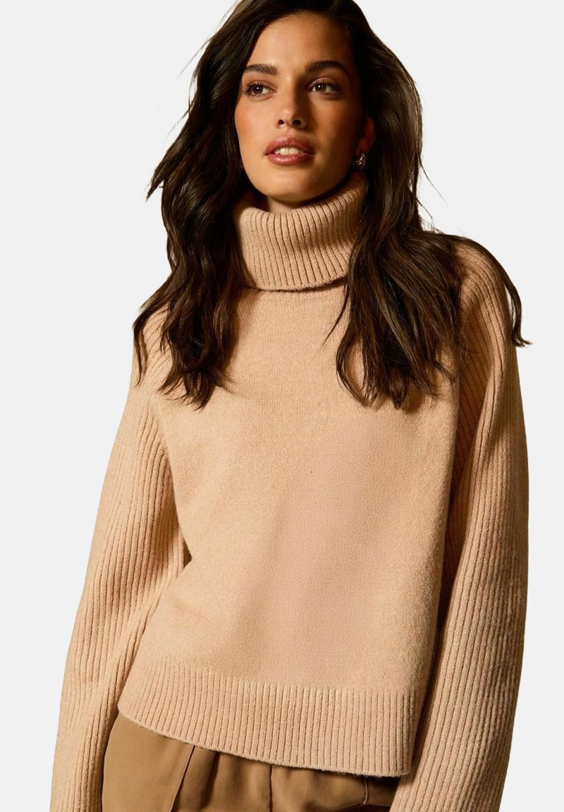 Maglione beige con collo alto e maniche e orlo a costine testurizzate. Design morbido e oversize, lunghezza cropped, adatto per essere indossato a strati.
