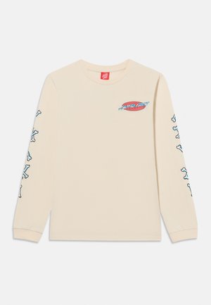 Béžová košeľa s dlhým rukávom s červeným logom "Santa Cruz" na hrudi a modro-bielymi prekríženými kosťami na oboch rukávoch.