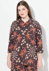 Hemd aus dunklem Stoff mit orangefarbenen und beigen Palm- und geometrischen Mustern, ausgestattet mit einem Kragen, einer Brusttasche und Dreiviertelärmeln.