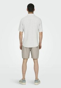 Kortærmet skjorte med krave i hvide og grå lodrette striber, parret med beige shorts. Casual stil med en afslappet pasform.
