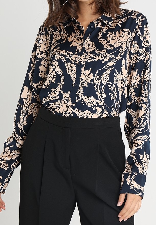 Námořnická blůza s růžovým květinovým vzorem, zapínání na knoflíky vpředu, dlouhé rukávy a jemná látka; v kombinaci s černými kalhotami s vysokým pasem.