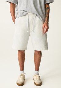 Kermittvärdiga shorts gjorda av mjukt tyg, med elastisk midja och snörning samt sidofickor. I kombination med beige sneakers.
