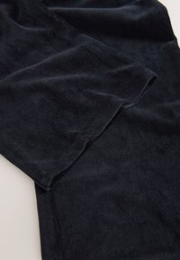 Tamnoplavi manšester s okomitom rebrastošću, karakteriziran mekom teksturom i glatkom završnom obradom. Rubovi su uredno ušiveni bez ukrasa.